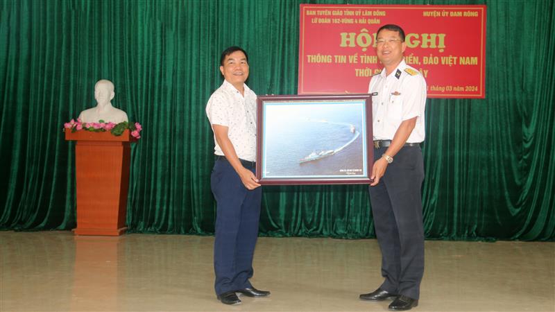Thượng tá Trần Trung Dũng - Phó Chính ủy Lữ đoàn 162 - Vùng 4 Hải quân tặng ảnh lưu niệm về biển, đảo của Tổ quốc cho Đảng ủy, chính quyền và Nhân dân xã Đạ Tông.